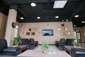 A reception area with a reception desk, seating, and wall-mounted plaques. - Enping Jinjiang Hotspring Hotel (Enping)