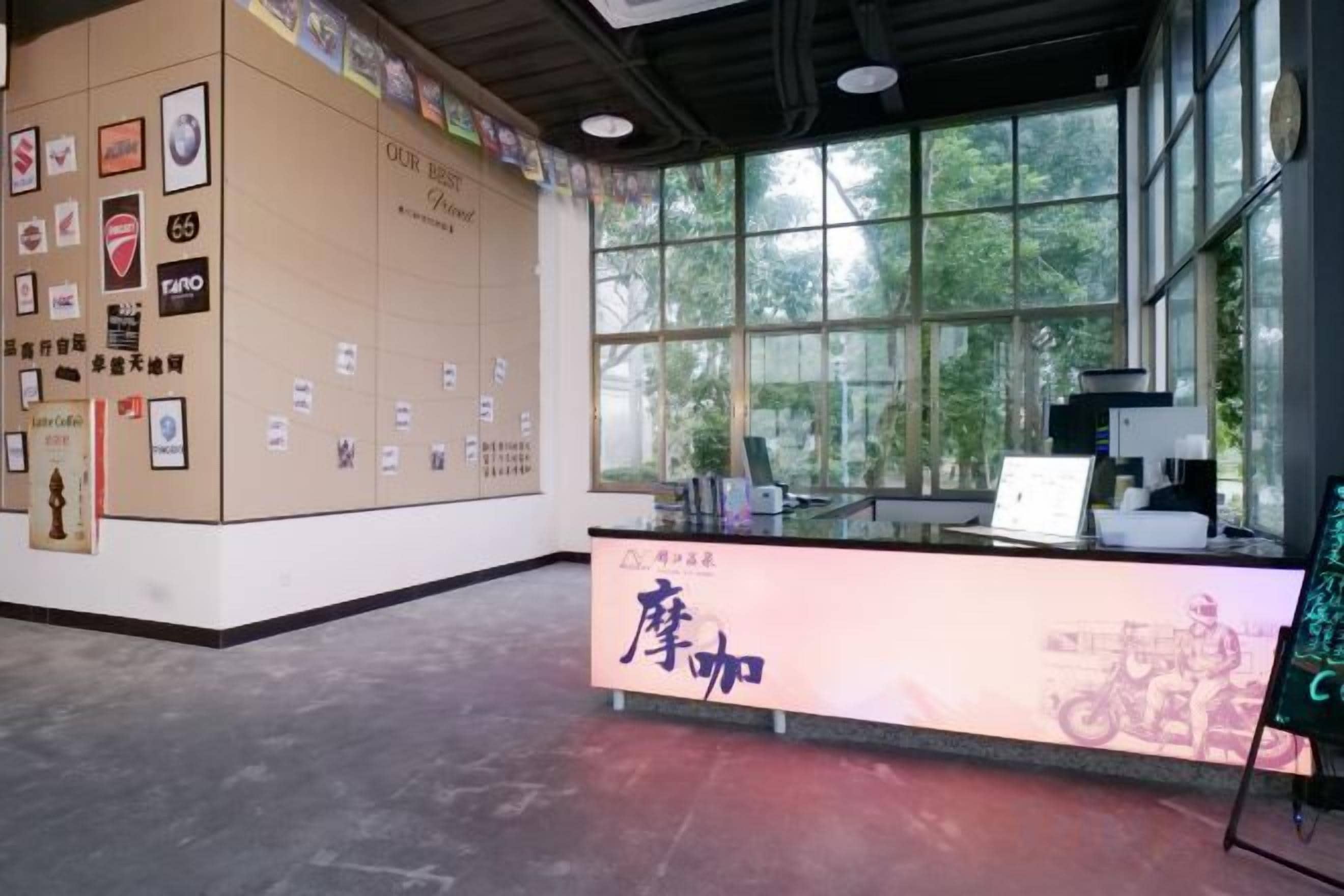 A reception area with a counter, framed pictures on the wall, and a window with a view of greenery.