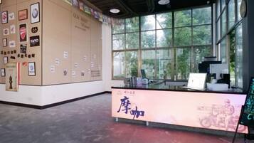 A reception area with a counter, framed pictures on the wall, and a window with a view of greenery.
