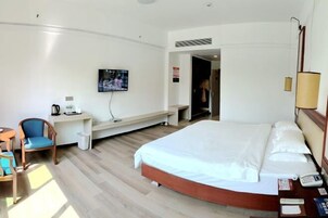 Habitación de hotel con cama, escritorio, silla, televisión y lámpara.