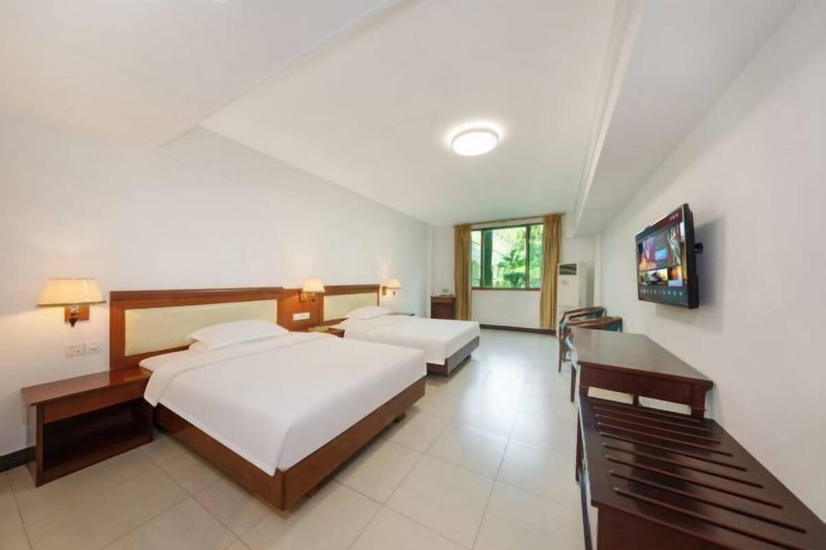 A hotel room with two beds, a desk, and a television.