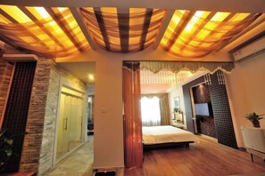 A hotel room with a bed, a TV, a wooden floor, and a ceiling with draped fabric. - Enping Jinjiang Hotspring Hotel (Enping)