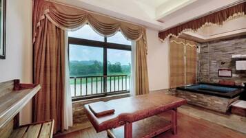 Relax in a serene space with a view of lush landscapes, featuring a massage table and stone bathtub.