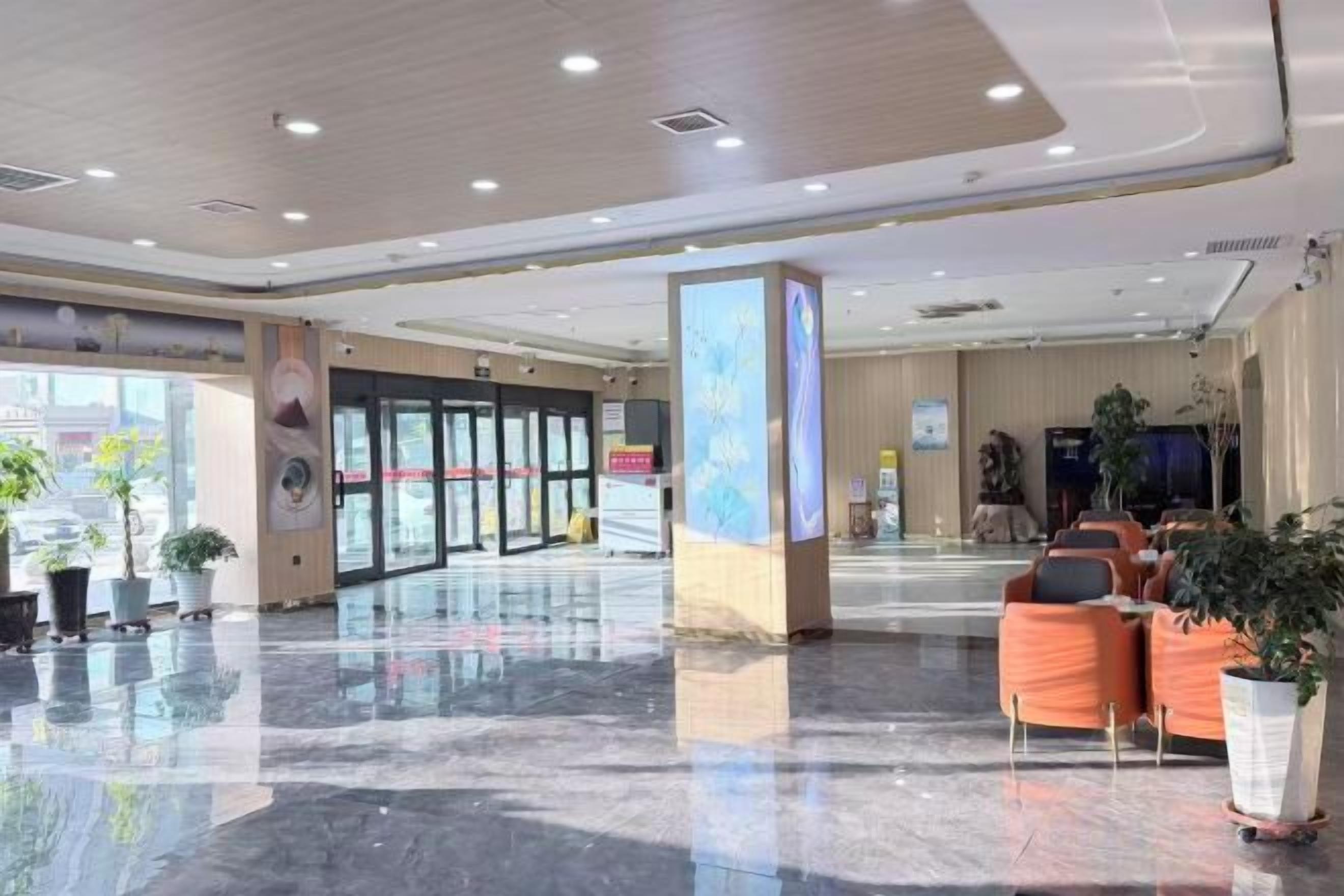 A hotel lobby with a reception desk, seating area, and potted plants.
