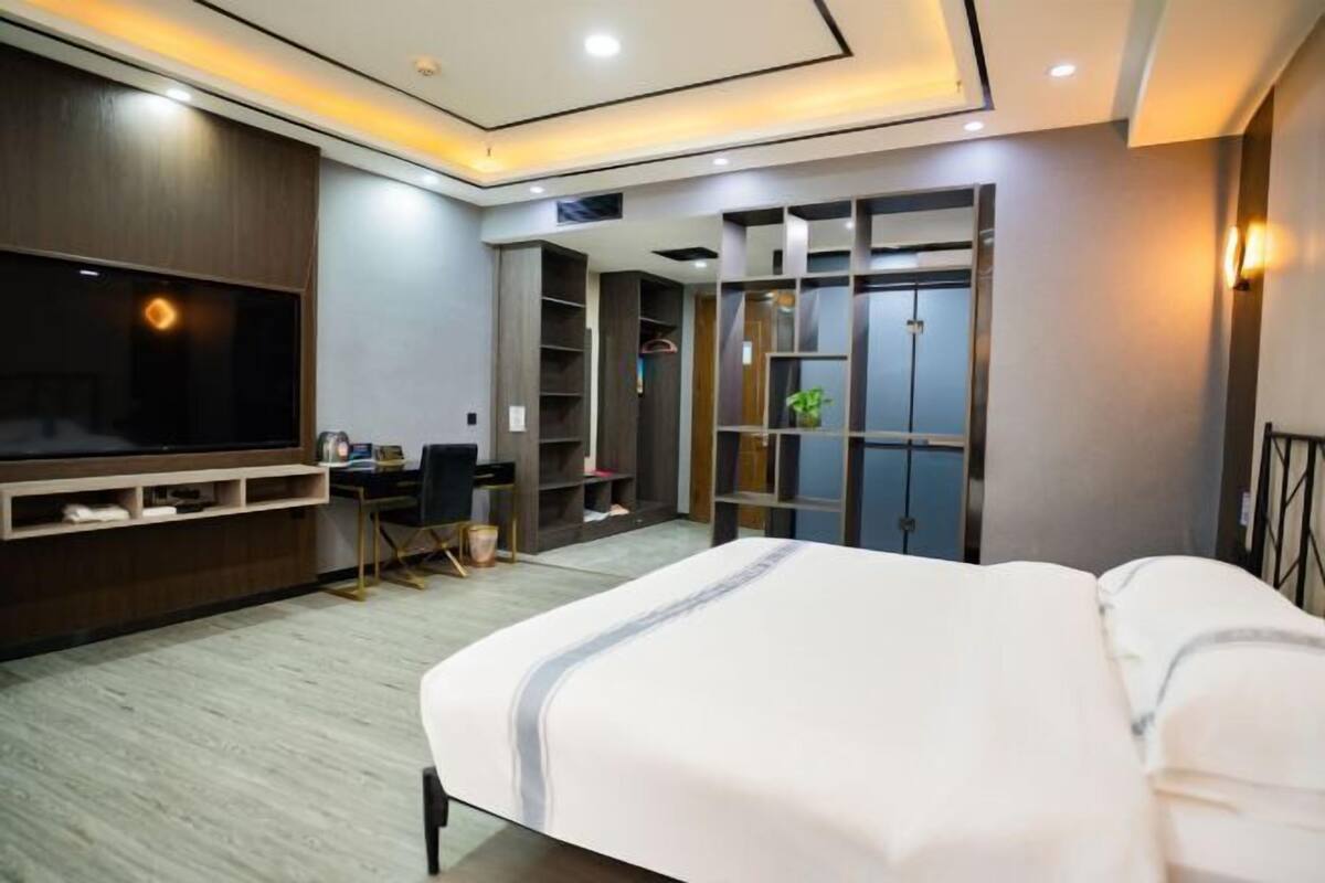 Una habitación de hotel moderna con una cama grande, un escritorio, un televisor y almacenamiento integrado.