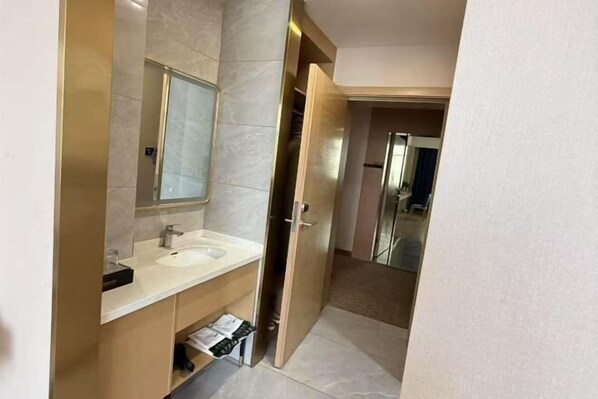 A modern bathroom with a sink, mirror, and open door leading to another room.