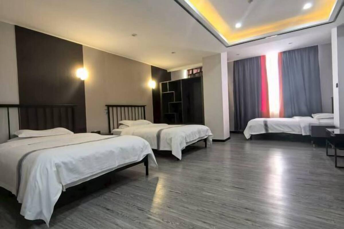 Una habitación de hotel con dos camas, un armario y un ventanal grande con cortinas.