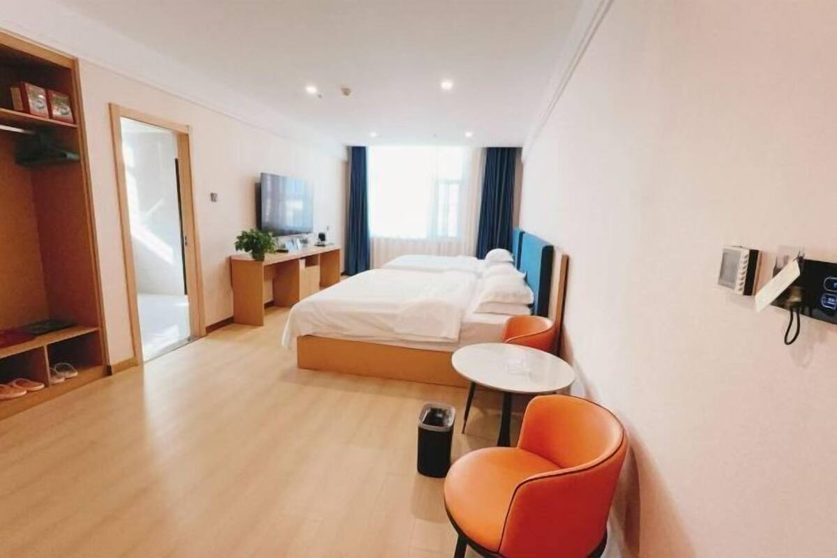 Una habitación de hotel con cama, escritorio, silla, mesita y un cesto de basura.
