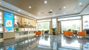 A spacious lobby with a polished marble floor, a reception desk, and seating area with orange chairs. - Jinse Yangguang Motel (Kuqa)