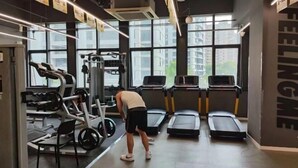 A gym with treadmills, weight machines, and a large window. - Jiujiantang Yijin Hotel (Hangzhou)