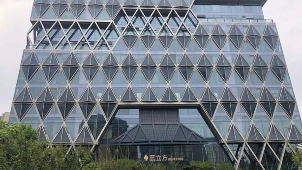 A modern building with a geometric facade and reflective glass windows. - Jiujiantang Yijin Hotel (Hangzhou)