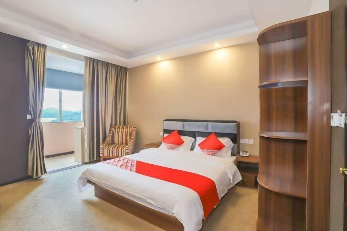 Ein Hotelzimmer mit einem großen Bett, einem Holzschrank und Blick ins Freie.