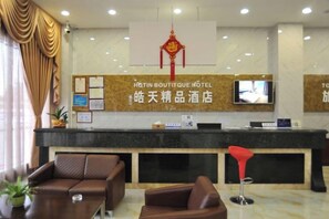 A hotel reception area with a reception desk, a television, and seating arrangements. - Dongguan Tian Boutique Hotel (Dongguan)