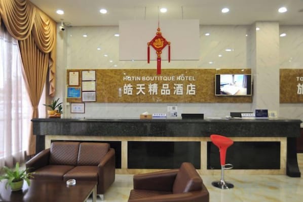 A hotel reception area with a reception desk, a television, and seating arrangements. - Dongguan Tian Boutique Hotel (Dongguan)