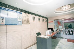 A reception area with a marble wall, a reception desk, and a glass door leading to a restaurant. - Dongguan Tian Boutique Hotel (Dongguan)