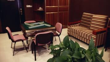 A room with a green felt table and chairs, a striped sofa, and a potted plant.