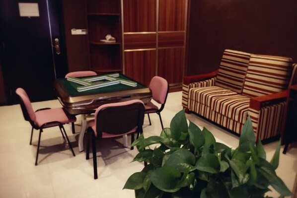 A room with a green felt table and chairs, a striped sofa, and a potted plant. - Dongguan Tian Boutique Hotel (Dongguan)
