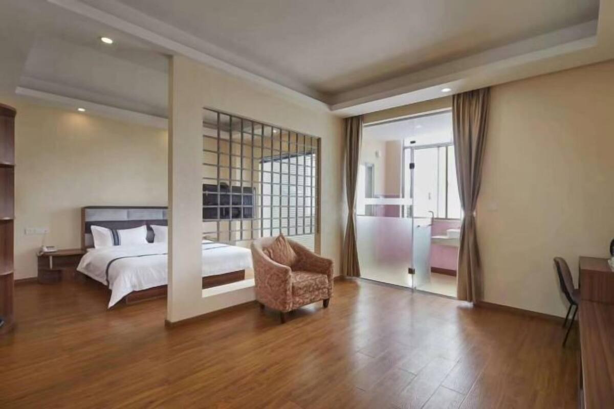 Ein Hotelzimmer mit Bett, Stuhl, einer Trennwand und Blick auf einen Balkon.