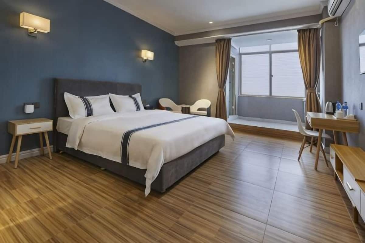Ein Hotelzimmer mit einem großen Bett, Nachttischen, einem Schreibtisch und einem Sessel.