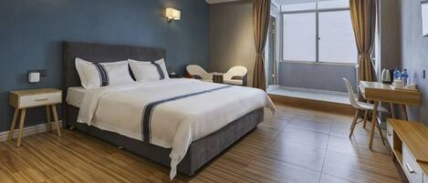 Ein Hotelzimmer mit einem großen Bett, Nachttischen, einem Schreibtisch und einem Sessel.
