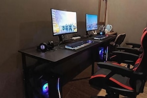 A gaming setup with two monitors, a keyboard, a mouse, and a gaming chair. - Dongguan Tian Boutique Hotel (Dongguan)