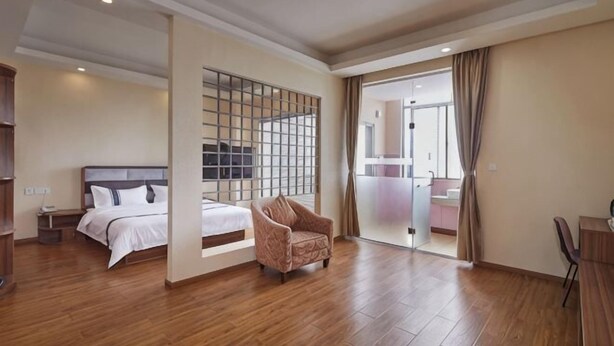 Une chambre d’hôtel avec un lit, une chaise, un bureau et une grande fenêtre.