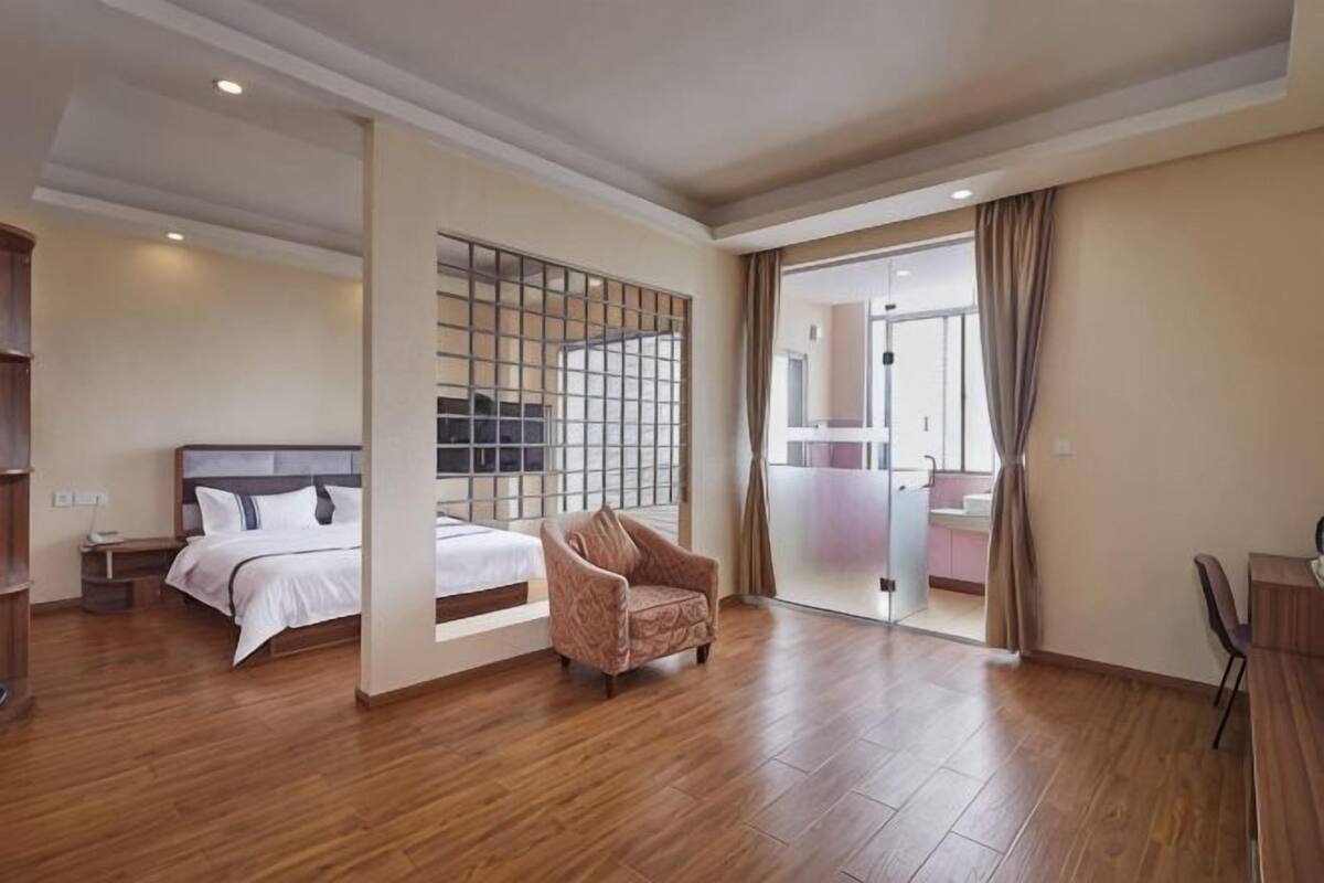 Ein Hotelzimmer mit Bett, Stuhl, Schreibtisch und großem Fenster.