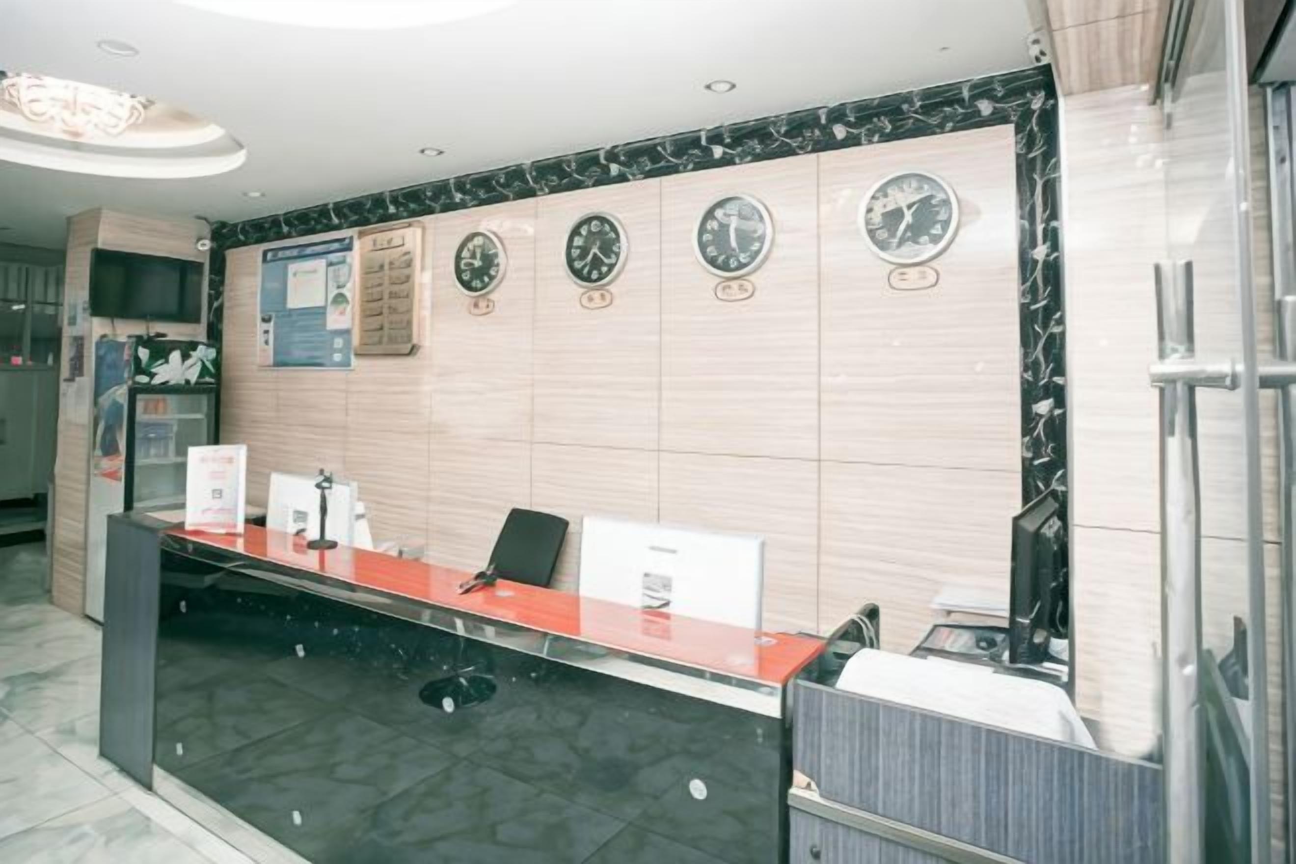 A reception area with a reception desk, chairs, a clock, and a wall-mounted information board.