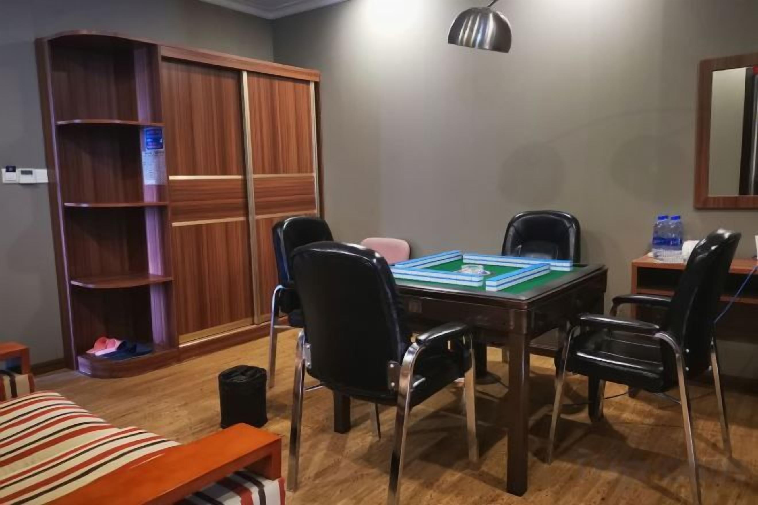 A room with a wooden table, chairs, a bookshelf, and a mirror on the wall.