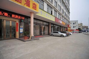 A hotel with a large entrance, multiple cars parked in front, and a signboard with Chinese characters. - Dongguan Tian Boutique Hotel (Dongguan)