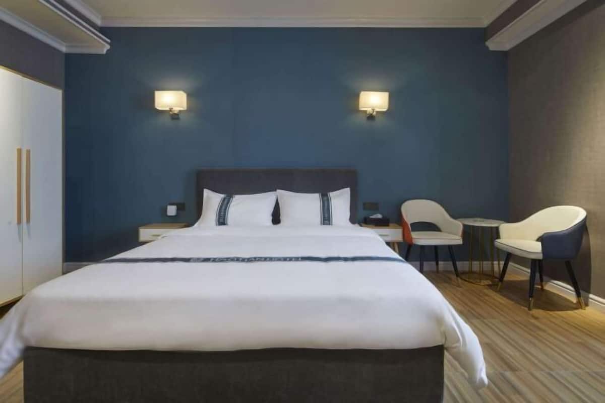 Ein Hotelzimmer mit einem großen Bett, zwei Nachttischen, einer Sitzecke mit zwei Stühlen und einem kleinen Tisch.