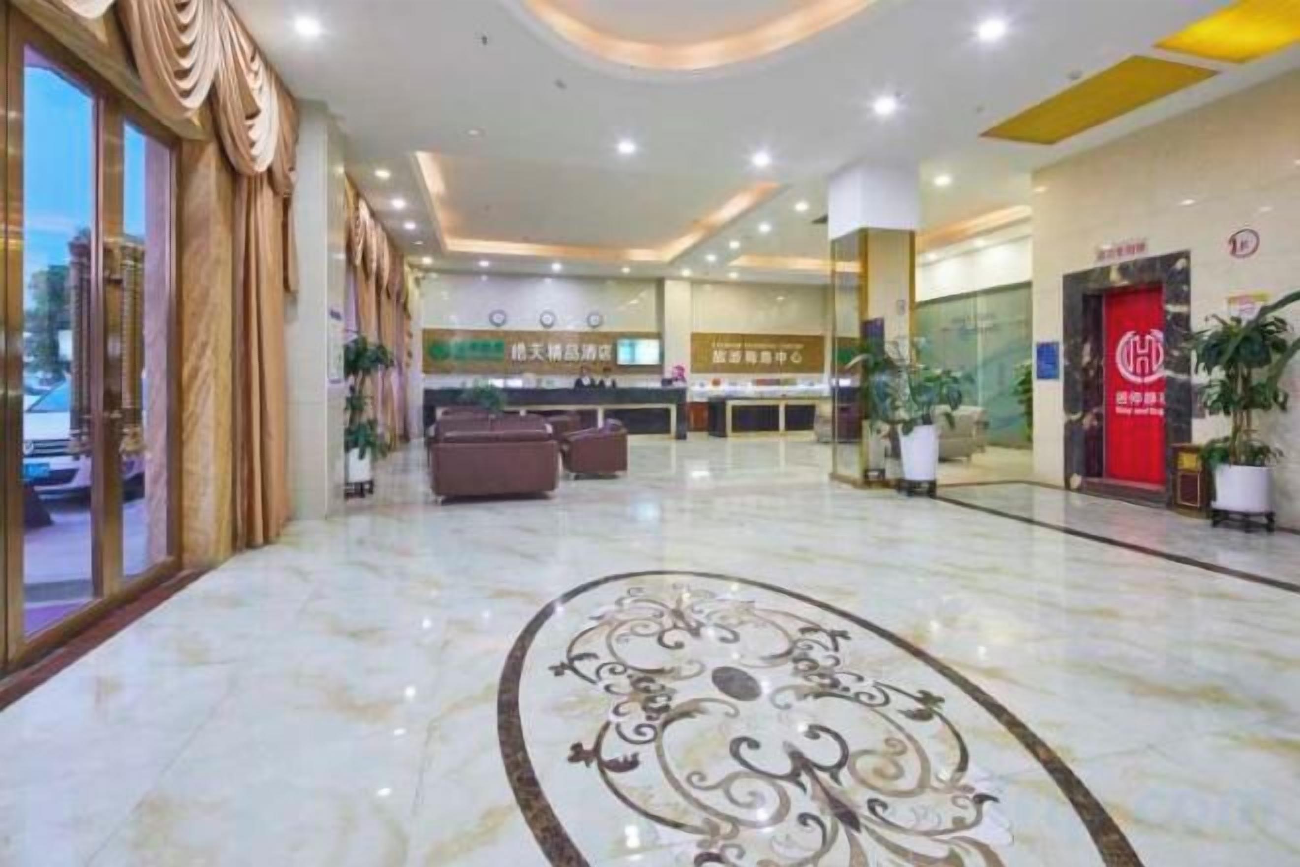 Een hotel lobby met een receptiebalie, een zithoek en een rode deur.