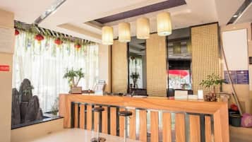 A reception area with a wooden counter, bar stools, and a large window with curtains.