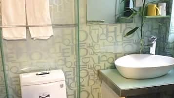 A bathroom with a glass shower enclosure, a white sink, and a toilet.