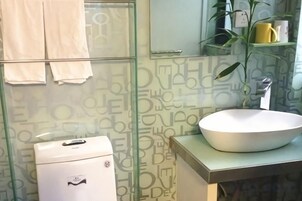 Un baño con cabina de ducha de vidrio, un lavamanos blanco y un inodoro.