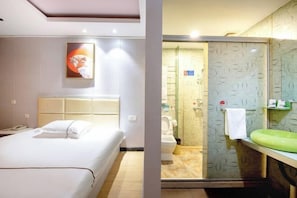 A hotel room with a bed, a bathroom with a shower, and a green sink. - Boyue Zhenpin Hotel (Zhangyang Road) (Linhai)