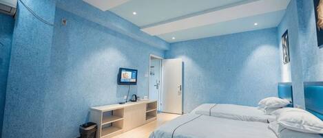 A bedroom with a bed, a desk, a chair, a television, and a door.