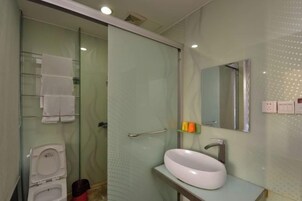 Un baño con cabina de ducha de vidrio, un lavabo blanco y un espejo.