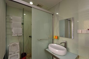 A bathroom with a glass shower enclosure, a white sink, and a mirror. - Boyue Zhenpin Hotel (Zhangyang Road) (Linhai)