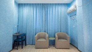 Ein Zimmer mit zwei Stühlen, einem kleinen Tisch und einem blauen Vorhang.
