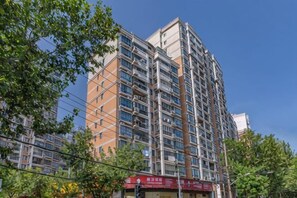 A high-rise building with multiple floors, large windows, and a visible storefront at the base. - Shenli Hostel (Shanghai)