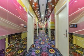 A brightly lit hallway with a colorful patterned floor, white doors, and a digital display on the wall. - Shenli Hostel (Shanghai)