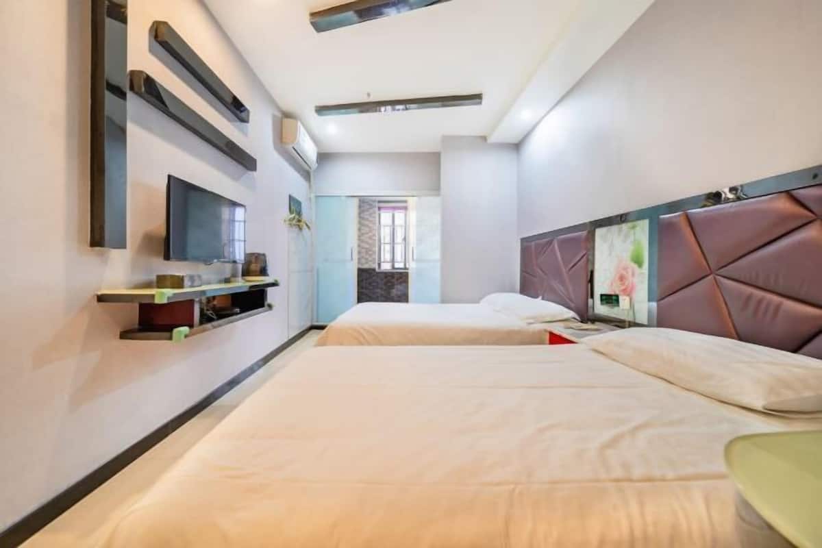 A hotel room with two beds, a TV, a flat-screen TV, and a decorative headboard.