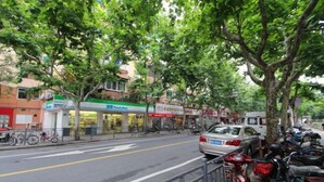 A street lined with trees and buildings, including a pharmacy and a restaurant. - Shenli Hostel (Shanghai)