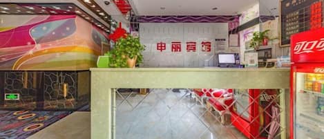A hotel reception area with a counter, a vending machine, and a decorative wall.