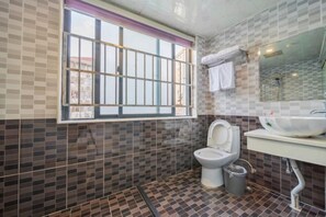 A bathroom with a tiled floor, a toilet, a sink with a mirror, and a window with bars. - Shenli Hostel (Shanghai)