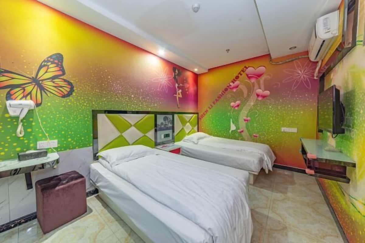 A hotel room with two beds, a vanity with a mirror, a telephone, and a wall with a butterfly mural.
