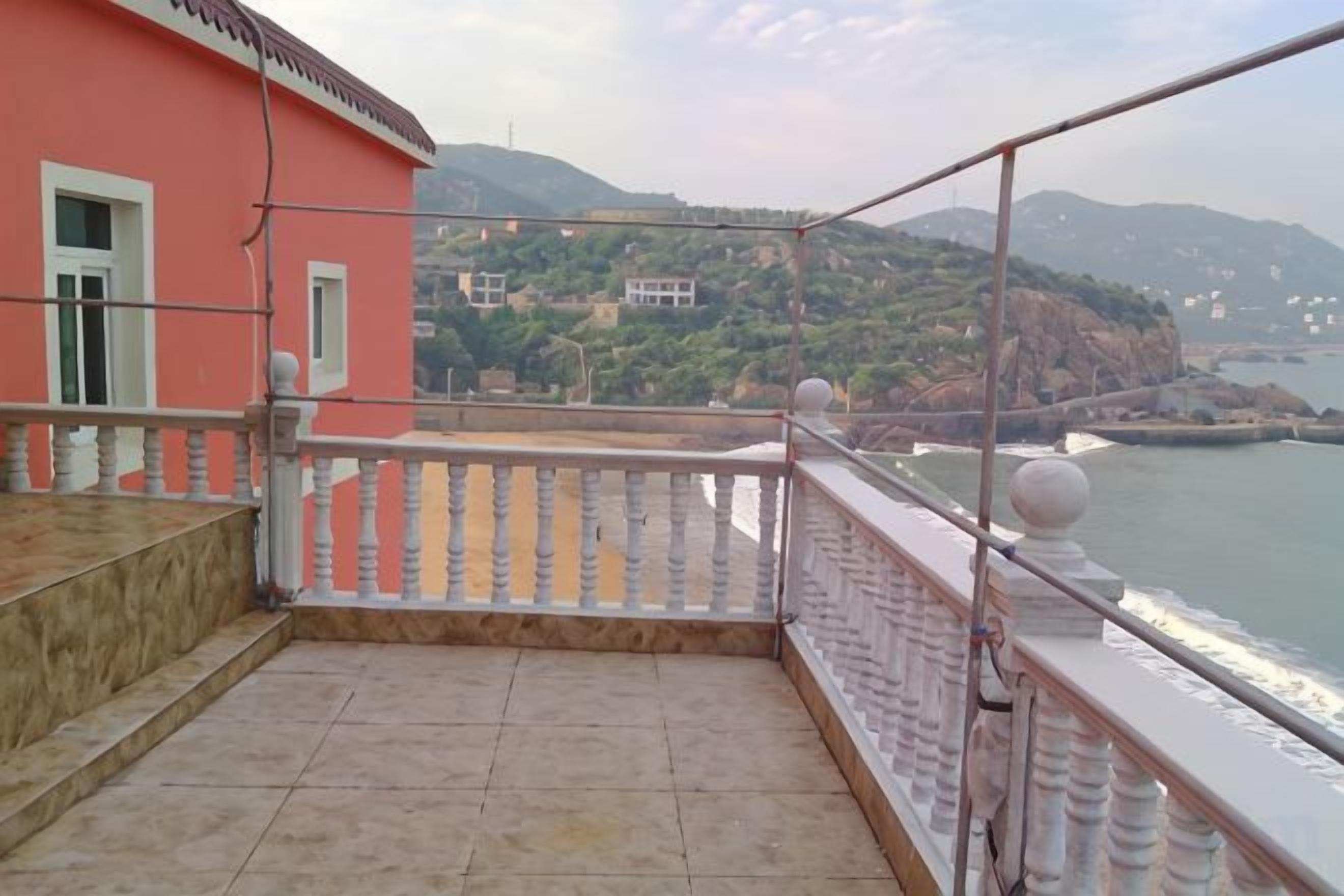A balcony with a view of a river and hills.