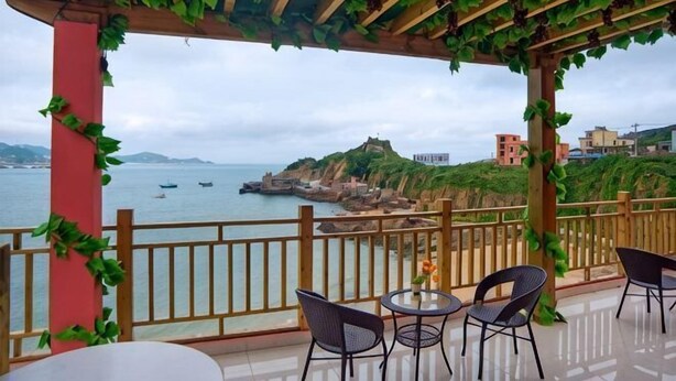 A terrace with a view of the sea, wooden pergola, and chairs. - Haiyi Jiage Inn (Shengsi)