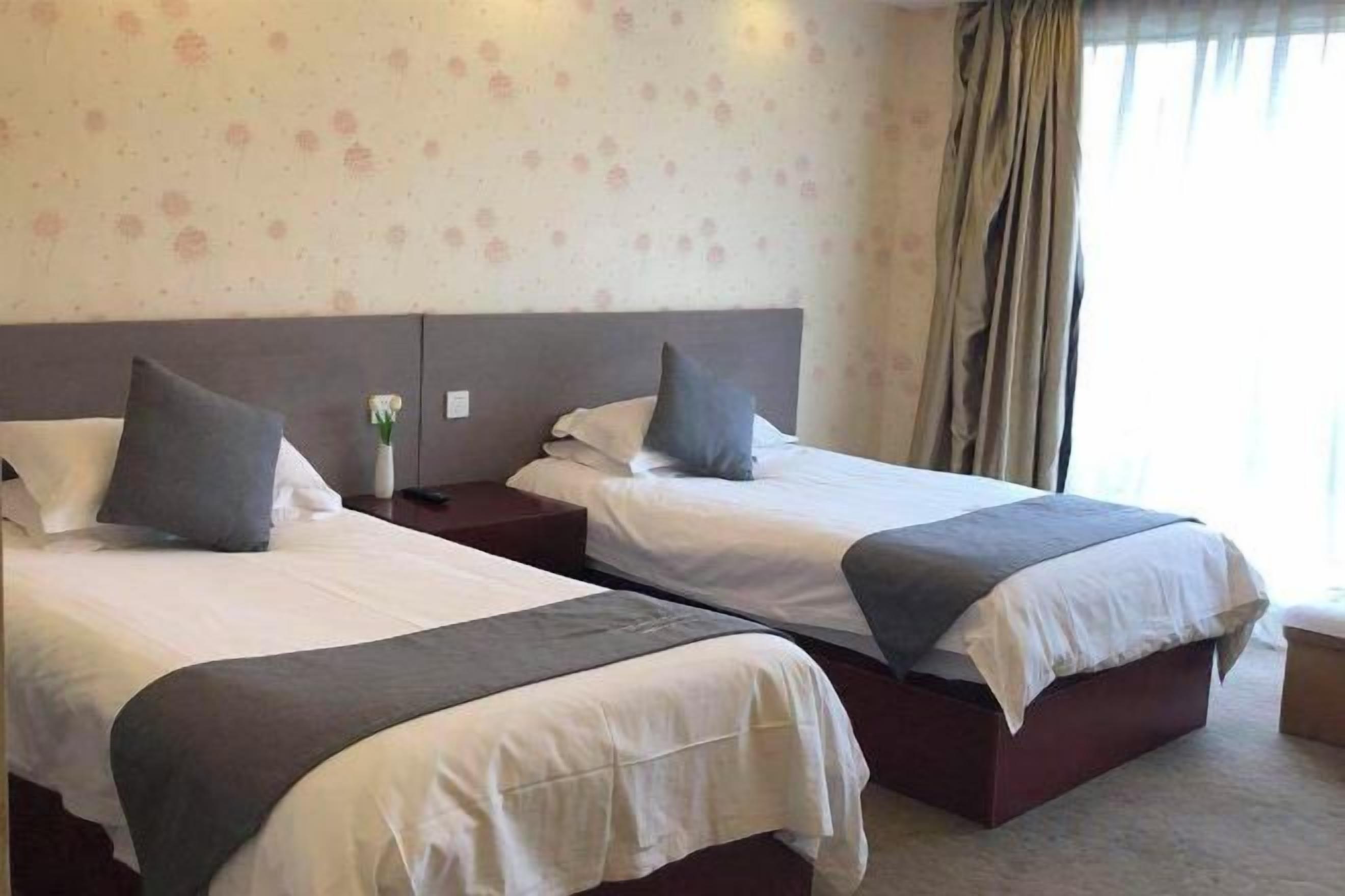 Una habitación de hotel con dos camas, cada una con una almohada y una mesita de noche.